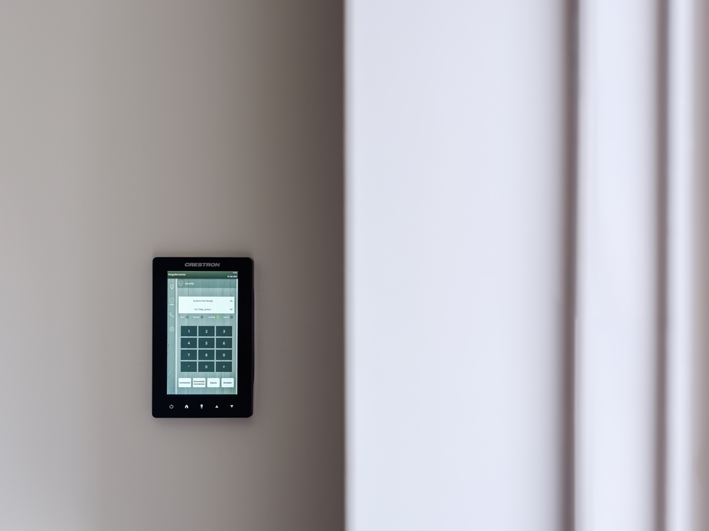 An alarm system linked with home automation hangs on the wall of a home.